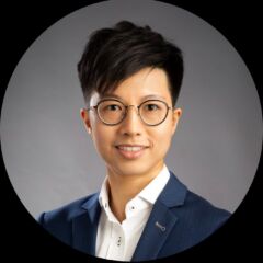 Nicole Chan in a blue suit and glasses smiling confidently.